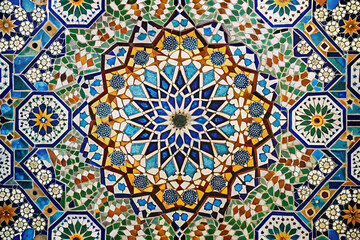 A colorful mosaic tile floor with a large flowery design. The design is made up of many small tiles, each with a different color and pattern. The overall effect is a vibrant and intricate work of art