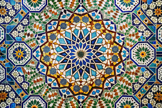 A colorful mosaic tile floor with a large flowery design. The design is made up of many small tiles, each with a different color and pattern. The overall effect is a vibrant and intricate work of art