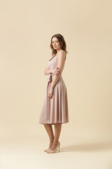 Fototapeta premium Female model wearing monochrome pale pink outfit. Classic sleeveless blouse and wide midi skirt. Fashion studio shot.