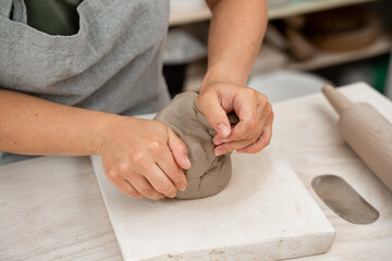 Wedging the clay before starting making a pottery project to create proper consistency. Removing air bubbles from clay before modeling to avoid the ruination of a ceramic product.