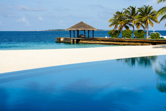 Infinity pool by the beach in an indian ocean island with reception pier at the background