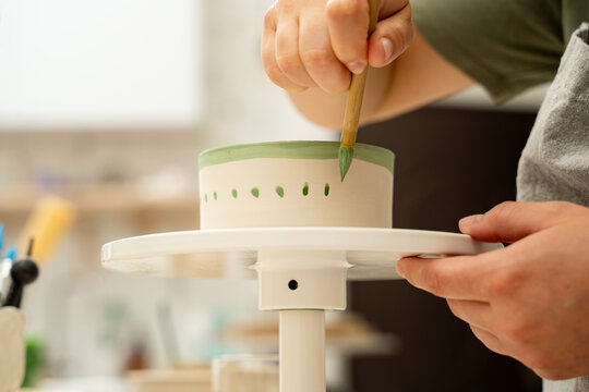 Painting ceramic products using acrylic paint and brush. Making a colorful decoration of a clay project with paint and water.