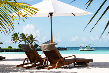 sunbeds under a parasol at the beach in Maldives