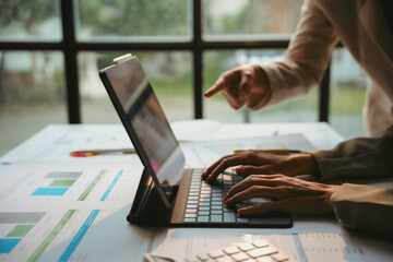 Business colleagues are reviewing financial data and analytics on a tablet, collaborating on a project in the office