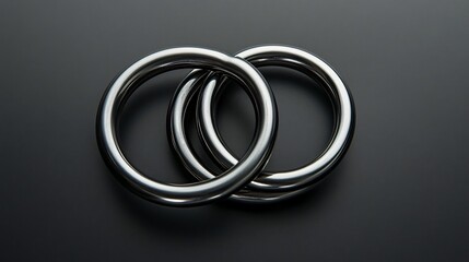 Fototapeta premium A set of metal rings linked together, isolated on a soft gradient black-and-grey background for a minimalist, clean magic trick display