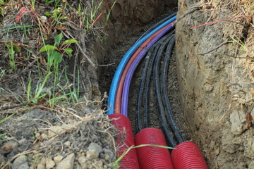 Cables and pipes in the ground on construction site. Electrical cables in the ground next to the...