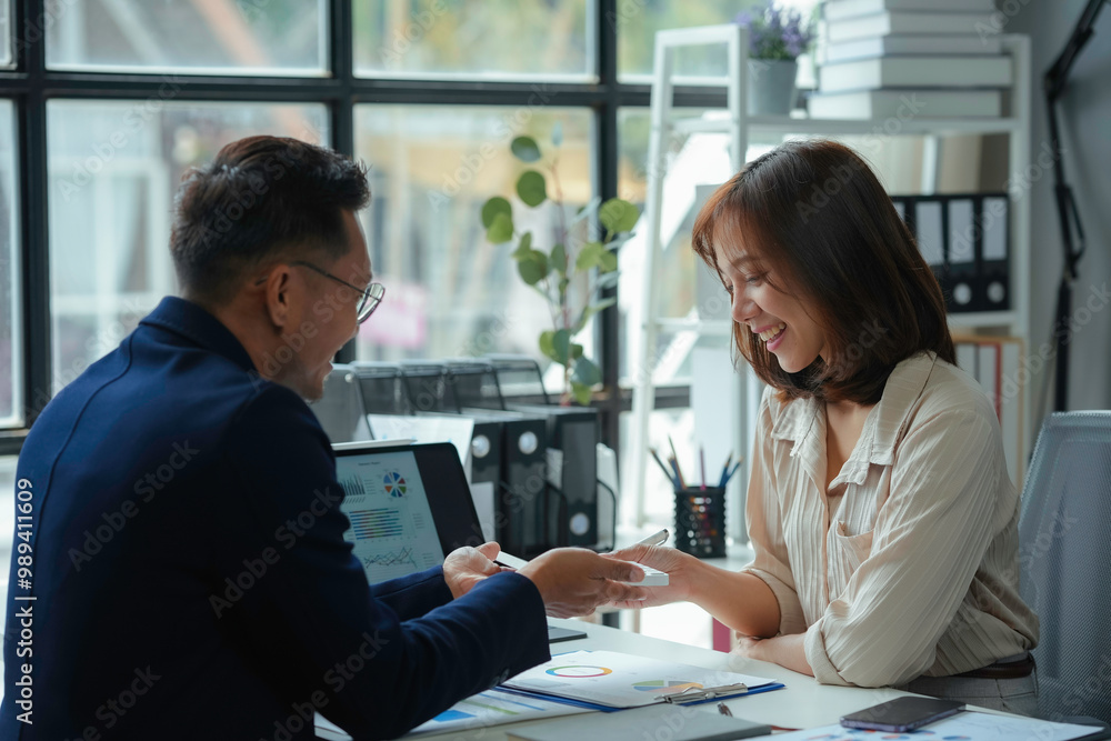 Poster two business partners smiling and discussing a project together, analyzing financial charts and usin