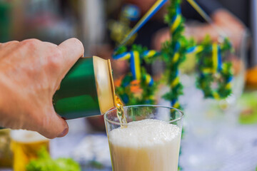 Close-up view of hand pouring beer from can into glass with frothy head during festive occasion.