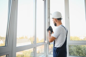 Construction worker repairing plastic window with screwdriver indoors, space for text.