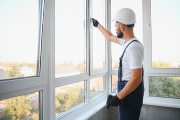 handyman adjusting white pvc plastic window indoors. worker using screwdriver to repair upvc window. homework maintenance