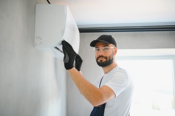 Technician man in uniform installing, repairing air conditioner. Construction and repair concept