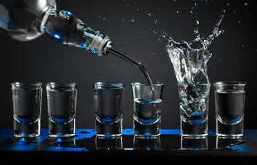 Barman pouring hard spirit into glasses.