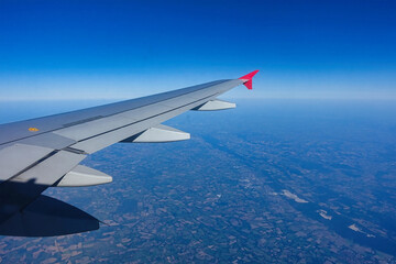 Obraz premium View of the airplane wing in clear weather with blue sky and sunshine..
