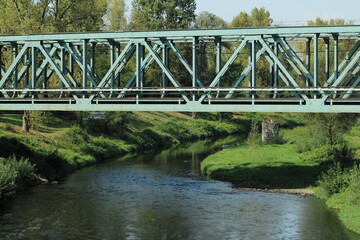 Green metal train bridge across the river 