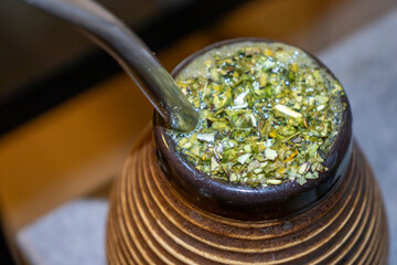 A close-up of a traditional yerba mate gourd filled with herbs, showcasing the unique texture and...