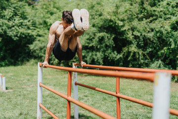 Fit, strong male sports person working out on parallel bars in a park, showcasing physical strength...