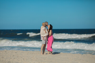 Happy parents carrying little doughter at beach