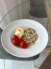 Oatmeal for breakfast with egg and tomatoes. A healthy balanced breakfast in the morning.