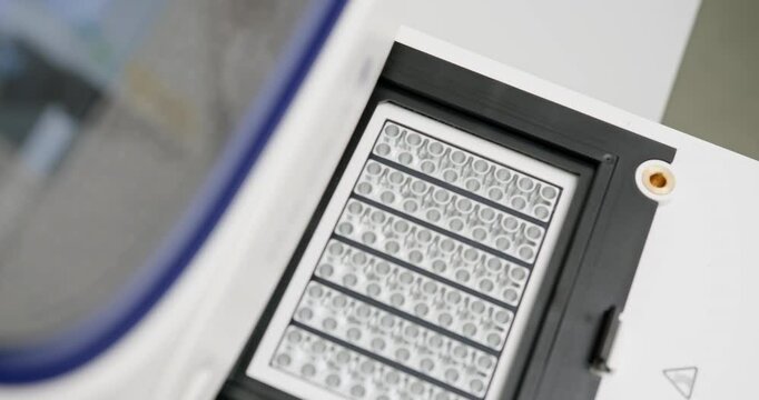 Laboratory technician wearing gloves placing microplate into automated machine for scientific analysis. Modern laboratory setup for accurate research and development. Laboratory Equipment For Analysis
