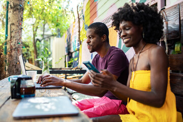 Couple working and relaxing together outdoors with a laptop and smartphone in a motel setting