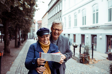 Senior couple laughing and exploring city with a map