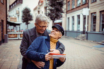 Senior couple laughing and exploring city with a map