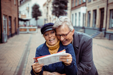 Senior couple laughing and exploring city with a map