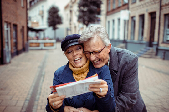 Senior couple laughing and exploring city with a map