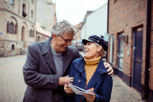 Senior couple laughing and exploring city with a map