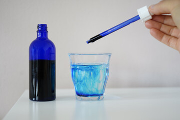 image showing a bottle filled with methylene blue  near a glass with water and methylene blue and a...