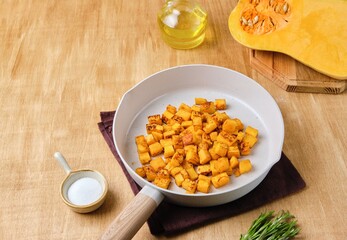 Preparing the filling for pumpkin ravioli or salad, fried pumpkin pieces in a light frying pan.