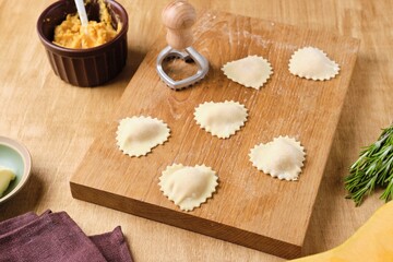 Cooking pumpkin ravioli, heart-shaped ravioli cut out on a wooden board. Pumpkin recipes.