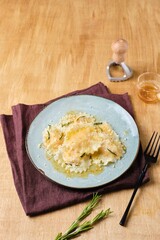 Cooking pumpkin ravioli, ready boiled ravioli, sprinkled with parmesan and drizzled with aromatic rosemary oil, on a gray ceramic plate. Recipes pumpkin.