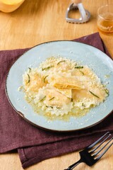 Cooking pumpkin ravioli, ready boiled ravioli, sprinkled with parmesan and drizzled with aromatic rosemary oil, on a gray ceramic plate. Recipes pumpkin.