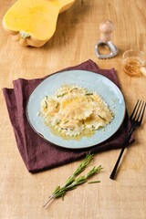 Cooking pumpkin ravioli, ready boiled ravioli, sprinkled with parmesan and drizzled with aromatic rosemary oil, on a gray ceramic plate. Recipes pumpkin.