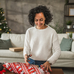 Mature woman wrap Christmas gift with festive decorations around her