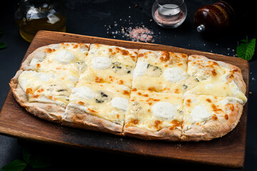 Italian cuisine pizza or pinza with different types of cheese on wooden board.