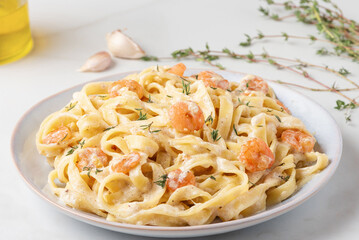Creamy shrimp Alfredo fettuccine pasta garnished with fresh thyme, parmesan cheese, garlic, olive oil, and a sprinkle of peppercorns. Italian food