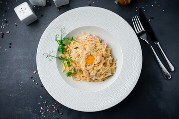 Pasta carbonara with ham, cheese, sauce, egg and herbs.