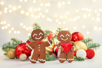 Two gingerbread men are smiling and standing next to each other on a table
