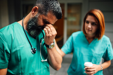 Nurse supporting a doctor in distress at a hospital entrance