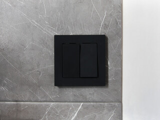 A modern black switch on a white wall background with gray granite. Technologies and electrics in...