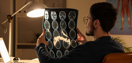 Male nurse with MRI scan working evening shift at table in clinic