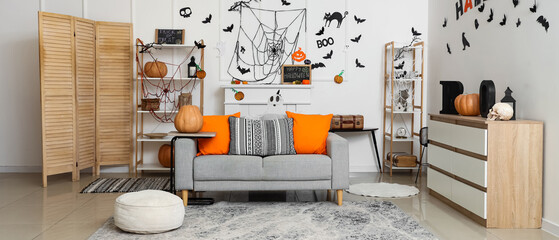 Interior of light living room decorated for Halloween with sofa and shelf units