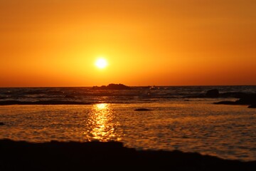 The sun is setting in the sea and the beautiful orange sky is making the whole sea corner beautiful