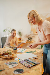 Fototapeta premium Happy female painter preparing art tool for painting at art studio.