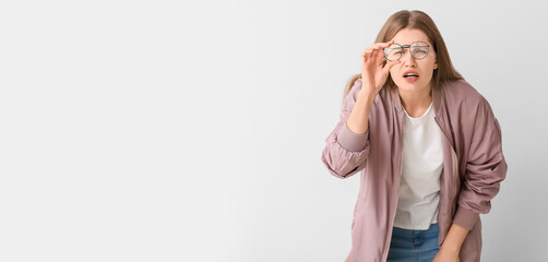 Woman with problem of poor eyesight on light background. Diabetes symptoms