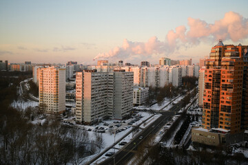 MOSCOW, RUSSIA - JANUARY 17th 2024: A stunning aerial winter view of a snow-covered street at sunset. The snow takes on soft pink hues, creating a tranquil and colorful scene, with no people in sight