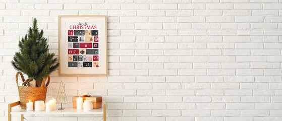 Shelf with fir tree, candles, gift and Christmas calendar on white brick wall