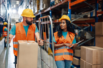 Diverse ollaborative warehouse workers reviewing logistics on clipboard